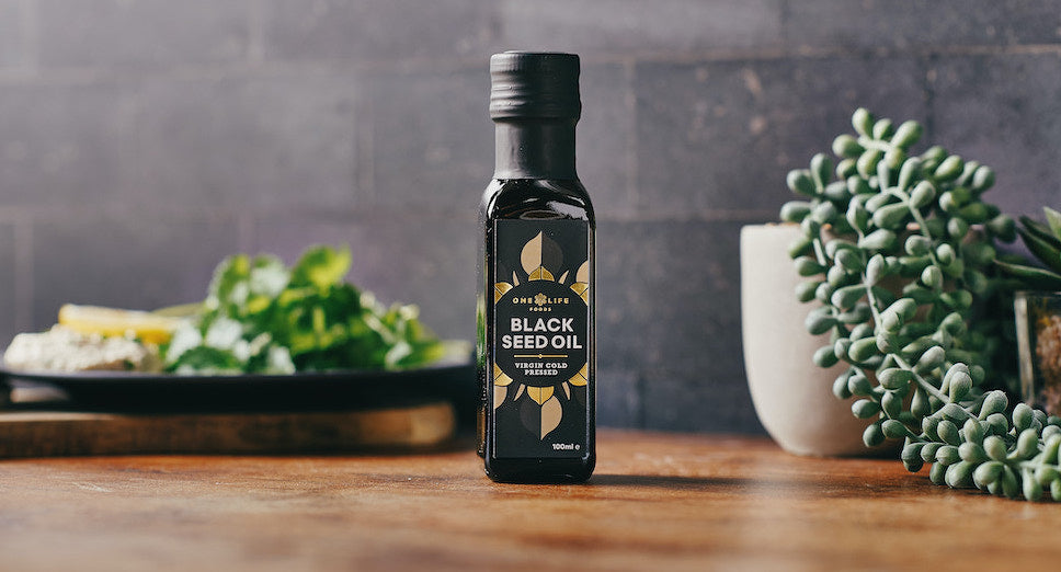 Black Seed Oil by One Life Foods placed on a kitchen table with natural ingredients.