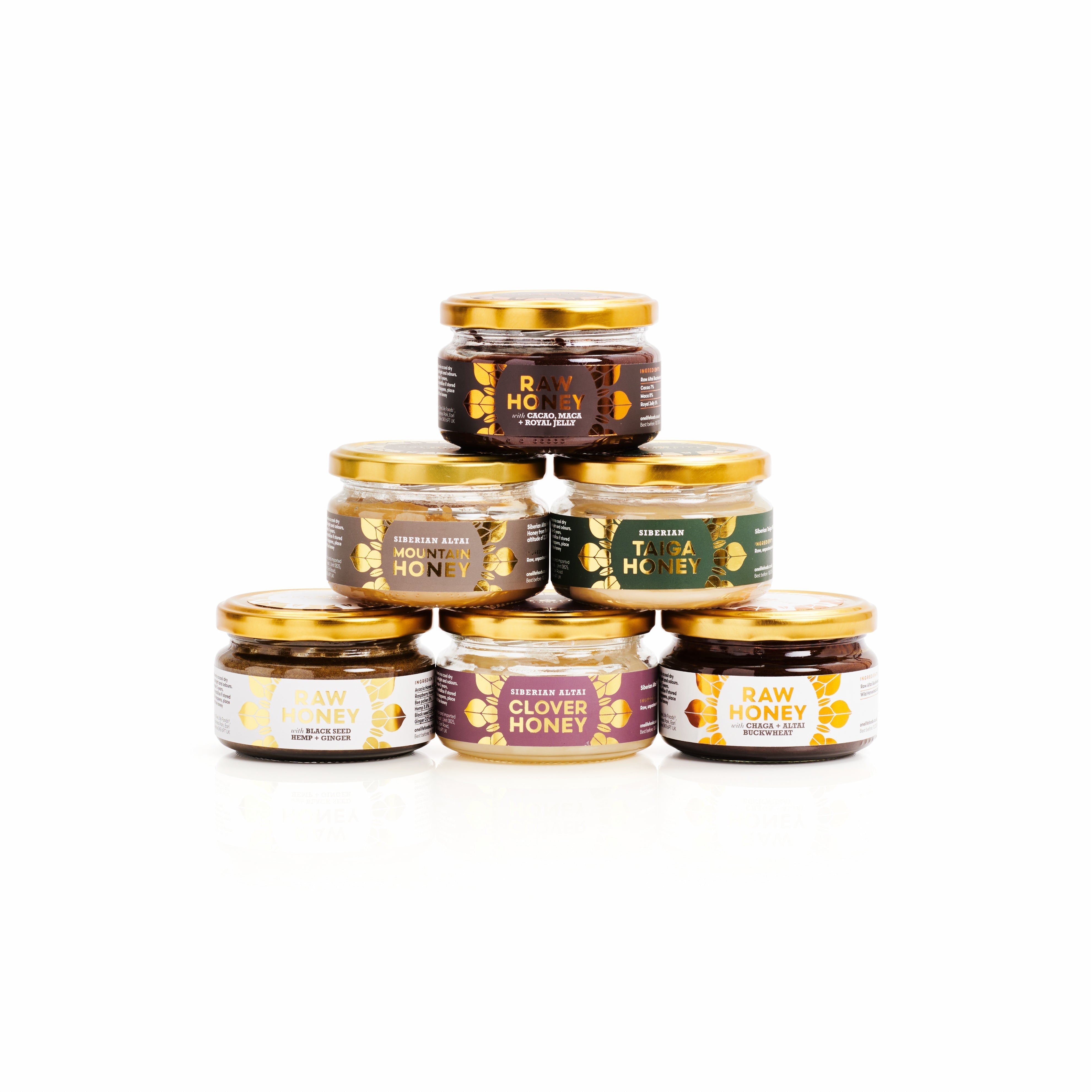 A selection of One Life Foods honey jars arranged in a pyramid on a white background.