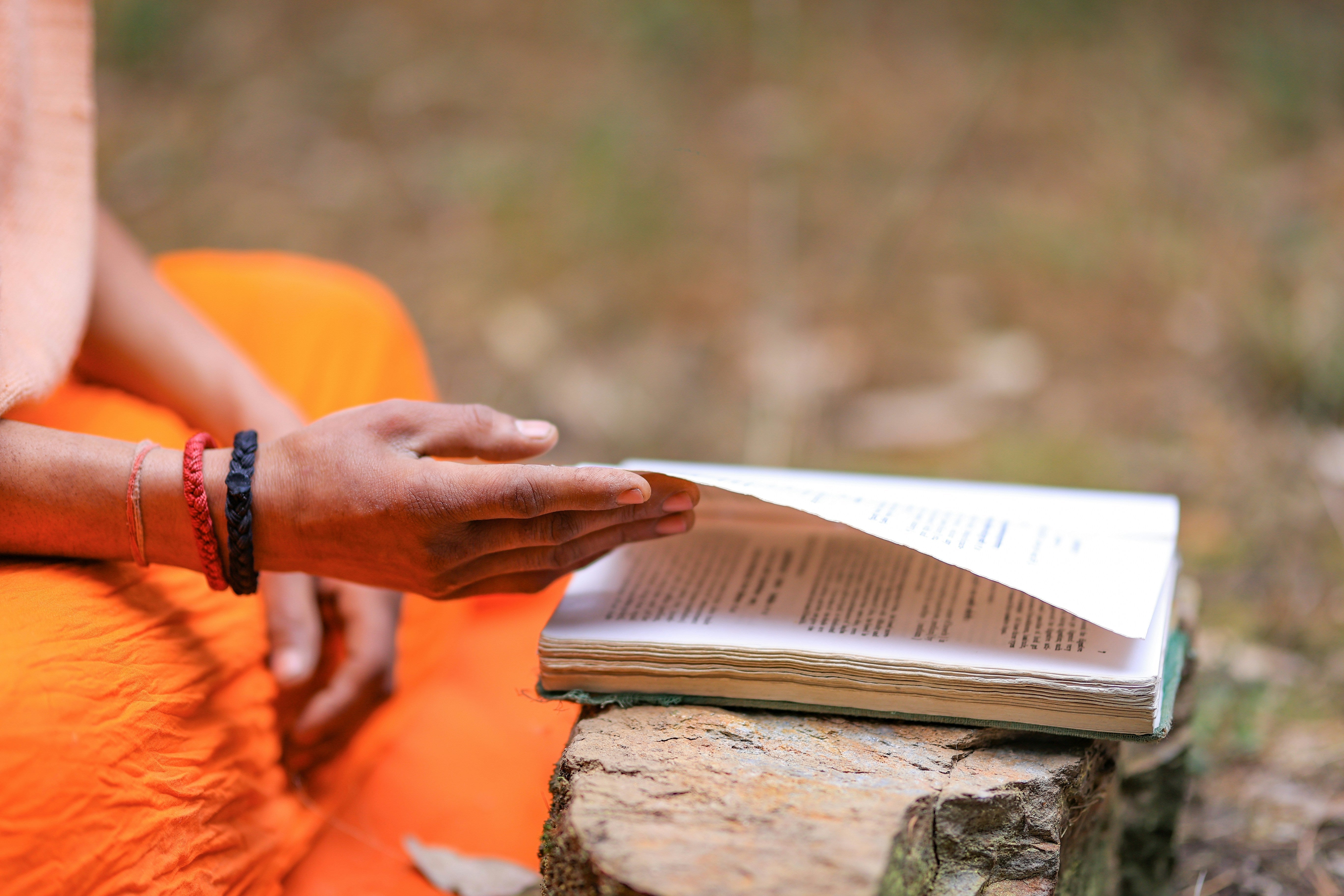 Person reading an Ayurvedic text outdoors, illustrating traditional Shilajit purification methods such as shodhana and Triphala processing.
