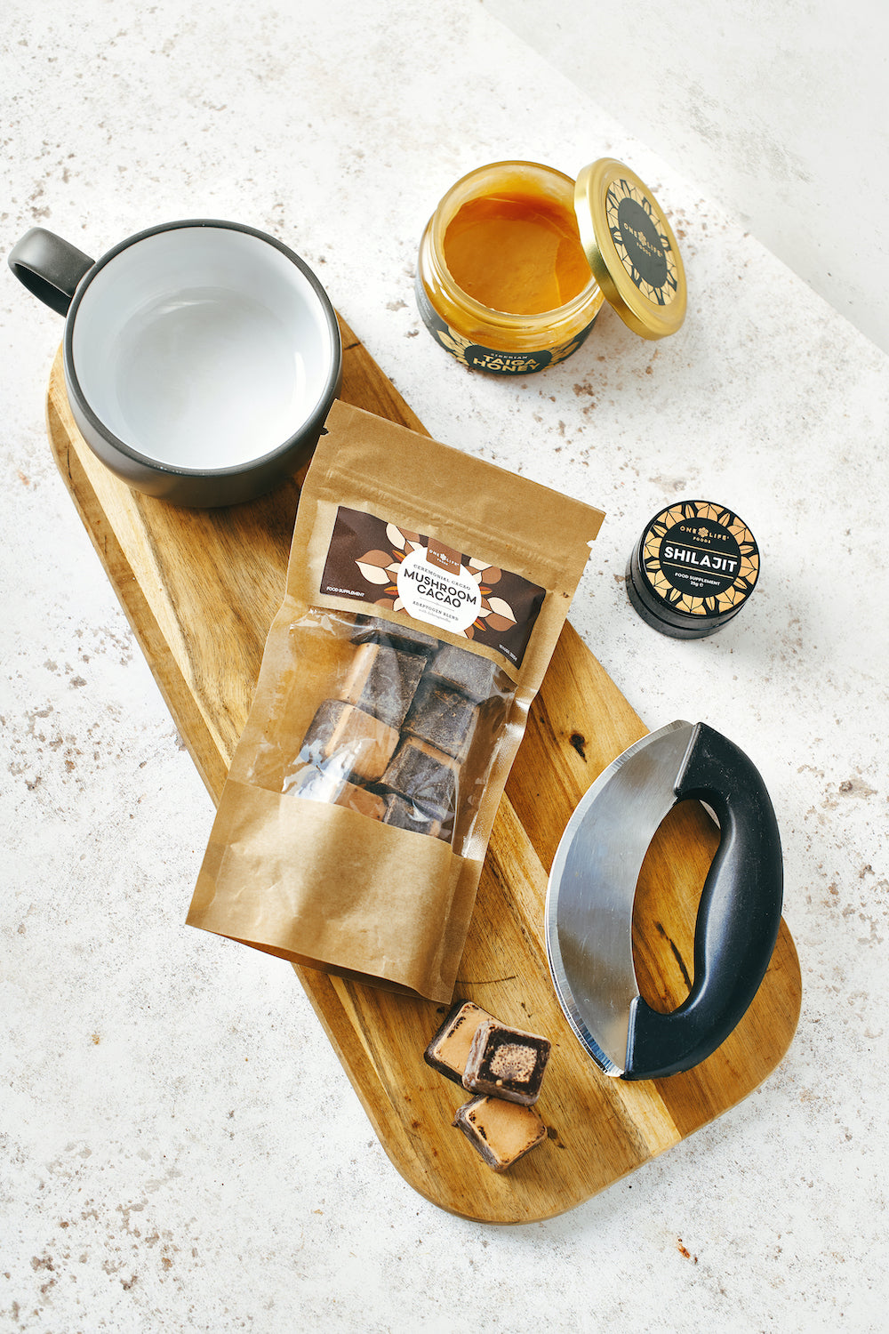 Cacao adaptogen blend with mug, honey and cacao nugs on wooden board